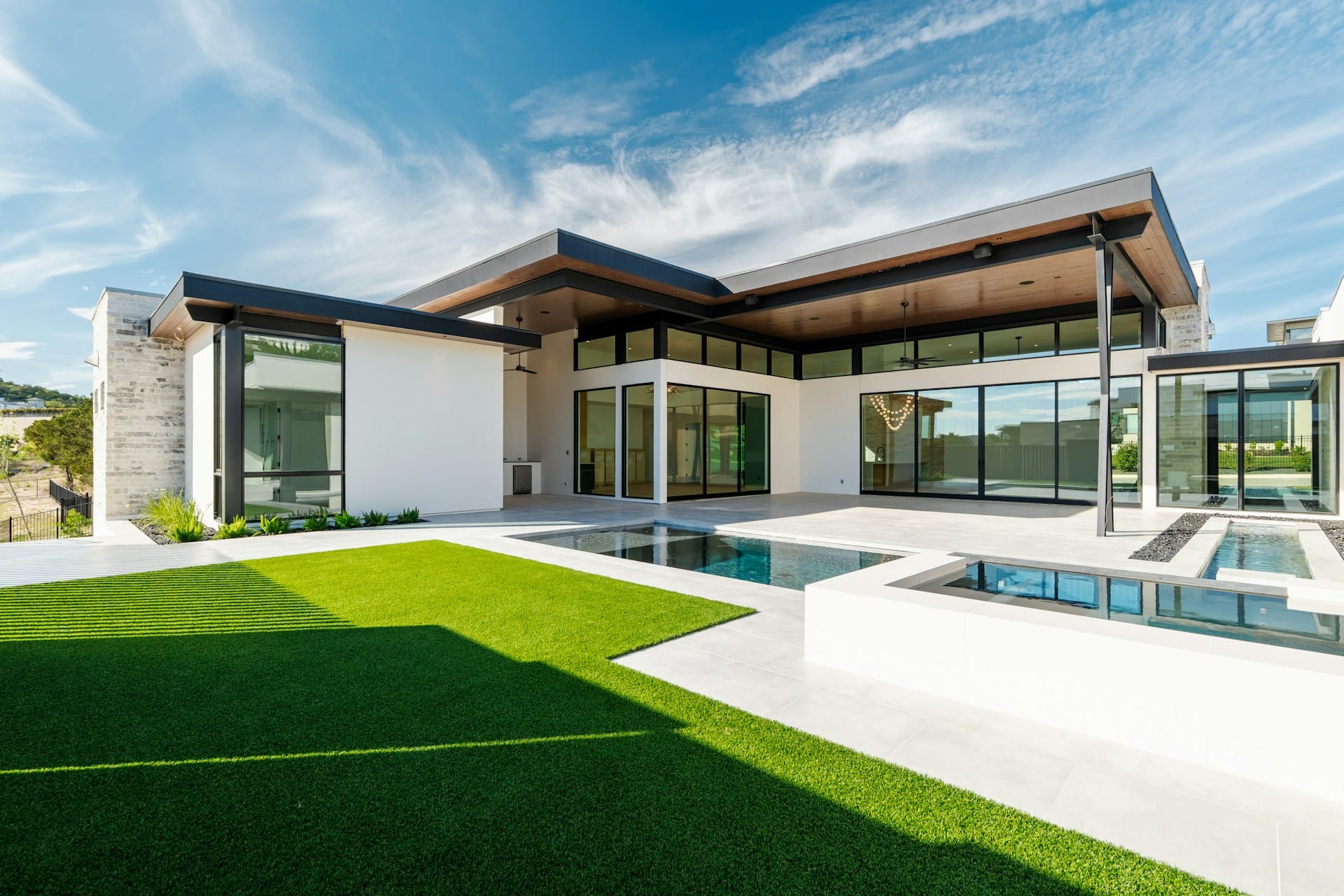 A modern Kingsbridge custom home exterior with a pool and courtyard
